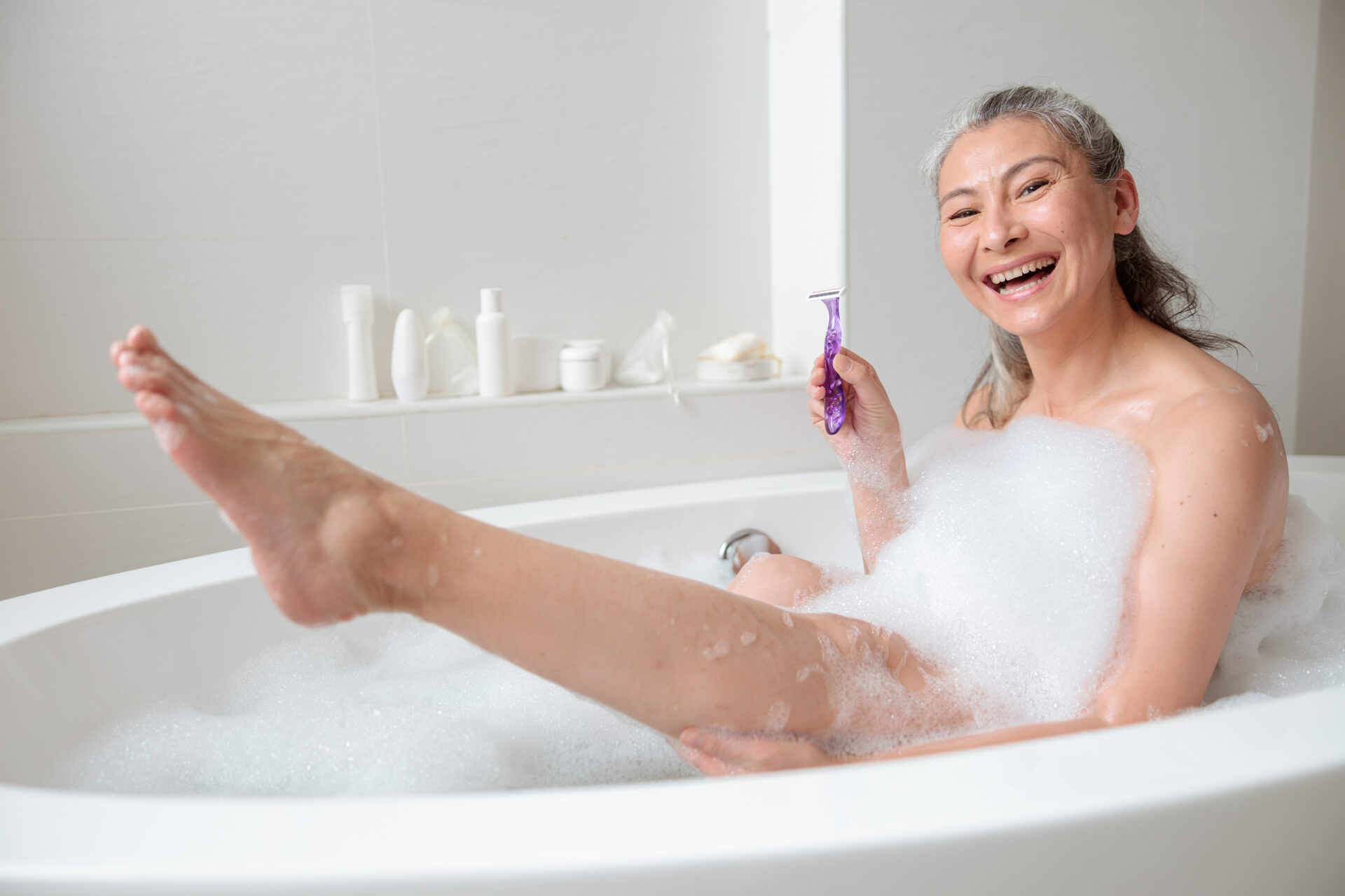 Femme dans son bain qui va se raser les jambes